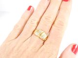 a woman ' s hand with a red manicure holding a gold ring