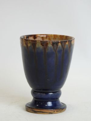 a blue and brown cup sitting on a white surface
