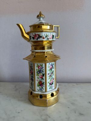 une théière dorée et blanche posée sur une table en marbre