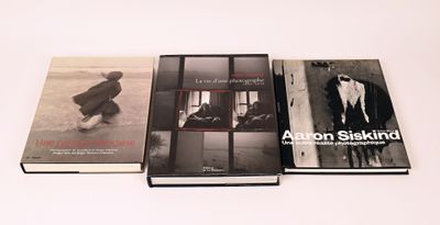 trois livres posés sur une table blanche, accompagnés d'une photo en noir et blanc les représentant