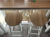 two stools sitting at a table with a vase of flowers on it