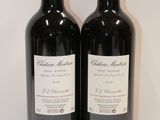 two bottles of red wine sitting on top of a white table