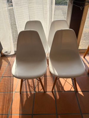 two white chairs sitting next to each other in front of a window