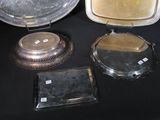 three silver trays and a silver plate on a black table