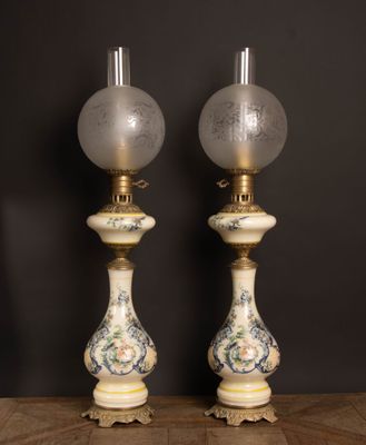 une paire de lampes anciennes en porcelaine posées sur une table en bois devant un mur noir