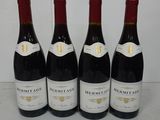 four bottles of red wine are lined up on a table