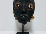 a black mask on a wooden stand on a white surface