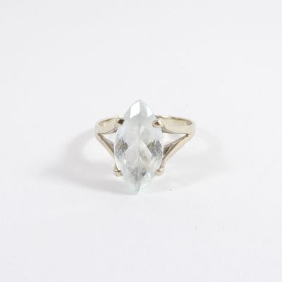 un gros plan d'une bague ornée d'une pierre transparente sur un fond blanc