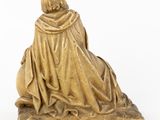 a gold statue of a man sitting on a rock with his back to the camera