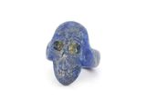 un gros plan d'une bague en forme de crâne en pierre bleue posée sur une surface blanche
