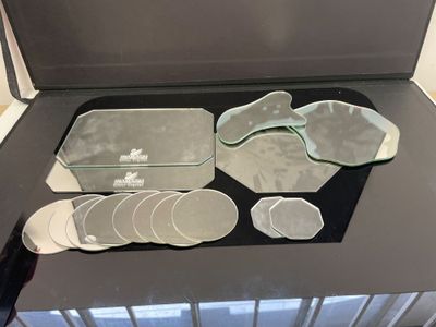 un plateau en verre sur lequel sont posés de nombreux dessous de verre et une paire de tongs