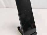 a black cell phone on a stand on a white surface