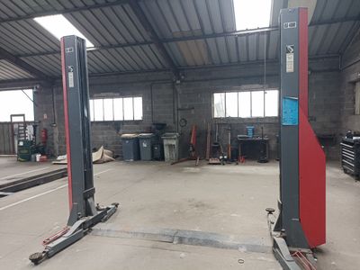 a picture of a garage with two lifts in the middle of it