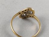 a close up of a gold and diamond ring on a white surface