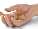 a hand holding a pair of gold earrings with red stones