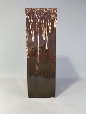 un vase brun posé sur une surface blanche