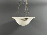 a white bowl hanging from a chain on a gray wall
