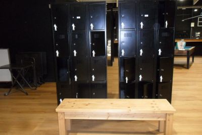 several black lockers and a bench in a room with wooden floors