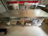 a large stainless steel table in the middle of a kitchen