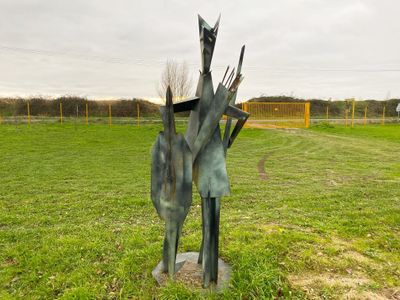 une statue représentant un homme et une femme dans un champ