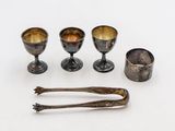 trois tasses en argent et deux cuillères posées sur un plateau blanc