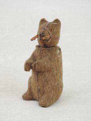 a teddy bear that is holding a piece of wood in its mouth