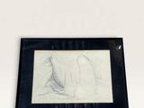 drawing of a woman laying on her stomach in a black frame on a white wall