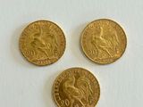 three gold sovereigns on a white surface