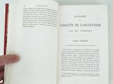 someone is holding an open book in their hand on a white surface