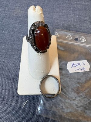 une bague avec une pierre rouge posée sur un morceau de plastique