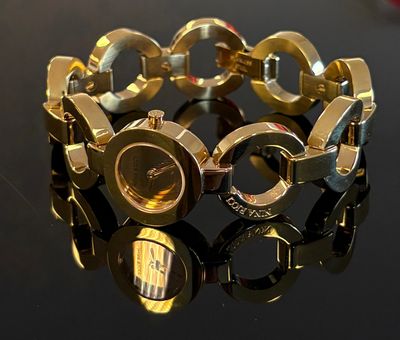 gros plan d'un bracelet en or sur une surface noire