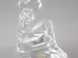 figurine en verre transparent représentant une femme assise sur un rocher, avec une fleur dans les cheveux