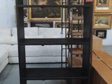 a black shelf with a glass door in the middle of a room
