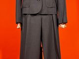 a suit on a mannequin stand against a red background