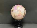 une boule en marbre rose et doré posée sur un socle noir
