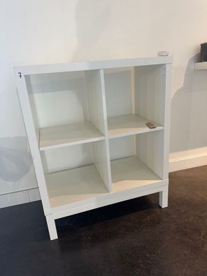 a white bookcase with four shelves in the corner of the room
