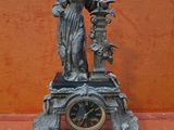 a statue of a woman holding a clock on a table