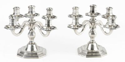 une paire de chandeliers plaqués argent sur des socles, sur fond blanc