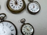 many different types of clocks displayed on a table