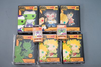 six figurines différentes de Dragon Ball dans des emballages en plastique, posées sur une surface grise