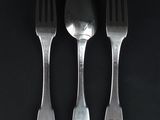 three silver spoons and a fork on a black surface
