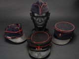 three military hats and a hat stand on a black surface
