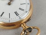 a gold pocket watch with roman numerals on it