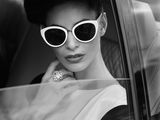 black and white photo of a woman in sunglasses sitting in a car