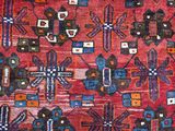 an image of a red area rug with blue and orange designs on it