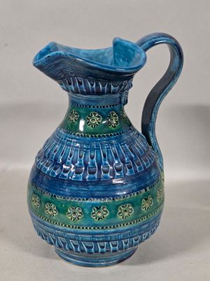 a blue and green vase with a handle on a table