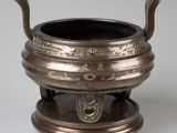 an antique bronze incense pot with a handle on a stand