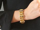 a woman wearing a gold bracelet and a black jacket