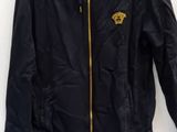 black jacket with gold logo and white sneakers on white background