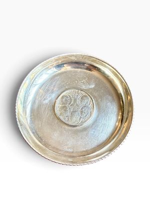 a silver plate on a white surface with a coin in the middle